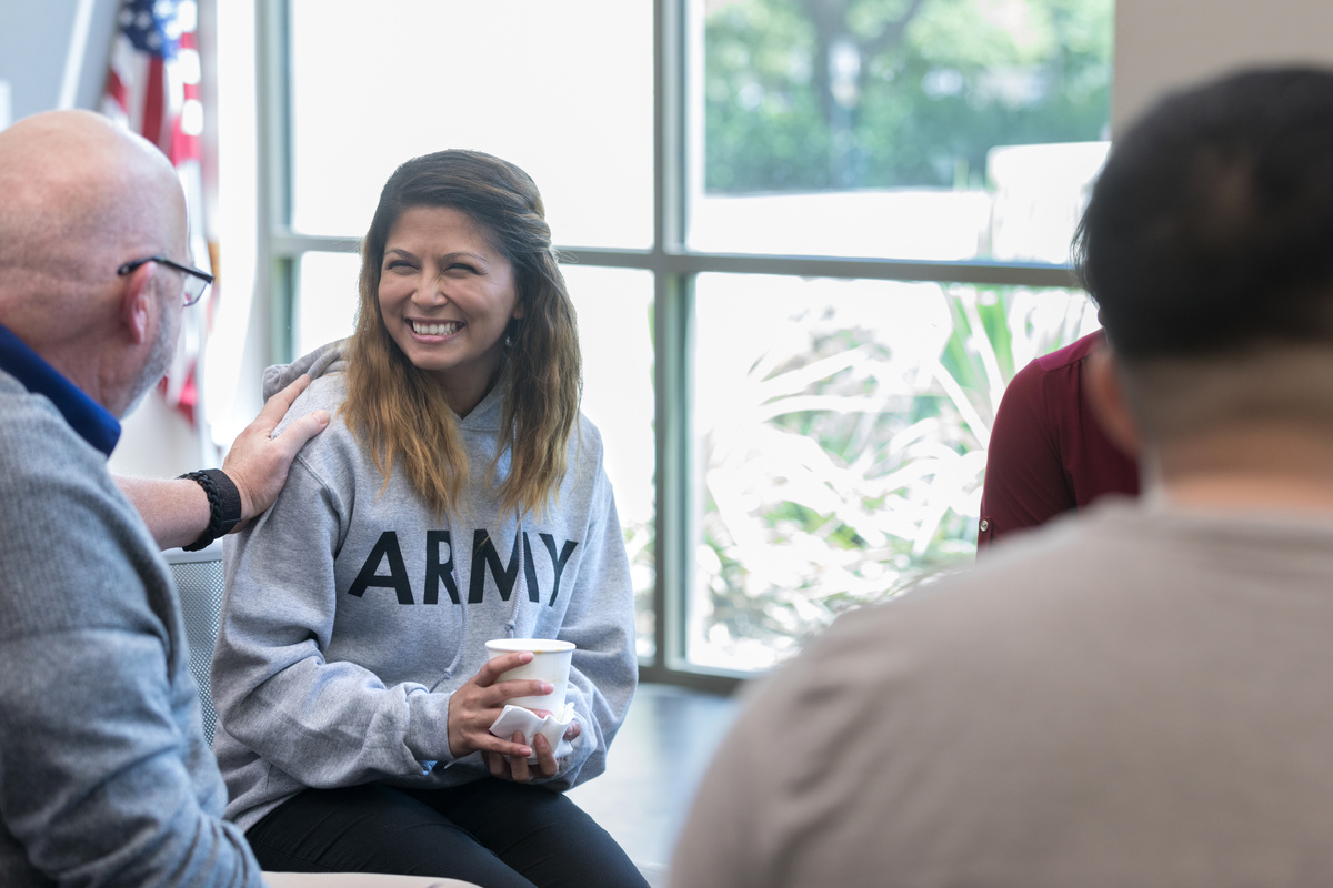 Older veteran reassures young veteran during therapy session